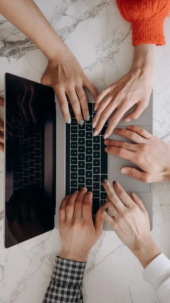 Mains de plusieurs personnes travaillant ensemble sur le clavier d'un ordinateur portable